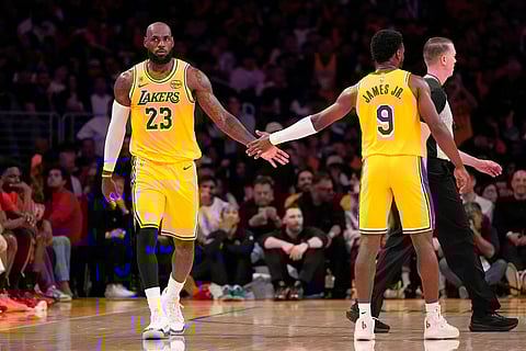 Los Angeles Lakers forward LeBron James, left, slaps hands with guard Bronny James during the first half in Game 1 of a first-round NBA playoffs basketball series against the Houston Rockets  in Los Angeles.