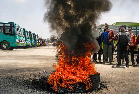 Flames and dark smoke billow out from a tyre after driver and conductors of private buses stage a protest against the government's proposal to expand Smart City bus services in other districts, in Srinagar.