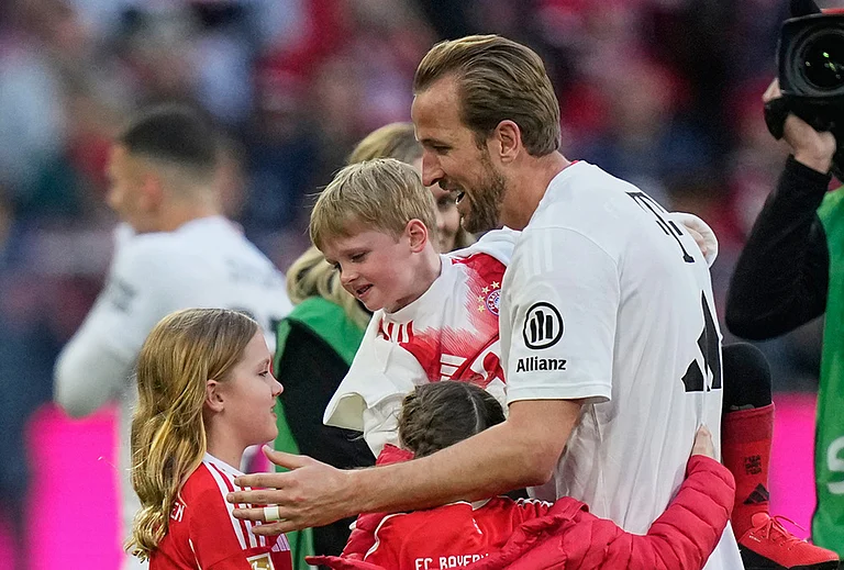 Bayern's Harry Kane hugs his kids after his team clinched the German league title after a Bundesliga soccer match between Bayern and Stuttgart in Munich, Germany. - | Photo: AP/Matthias Schrader