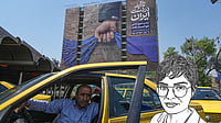 AP Photo/Vahid Salemi : A taxi driver waits for passengers in front of a billboard that shows a graphic depicting a military personnel's hand holding the Strait of Hormuz in his fist with signs which read in Farsi: "In Iran's hands forever," "Trump couldn't do a damn thing," "The control of Strait of Hormuz will be Iran's forever," in Vanak Square in northern Tehran, Iran, Thursday, April 16, 2026. 