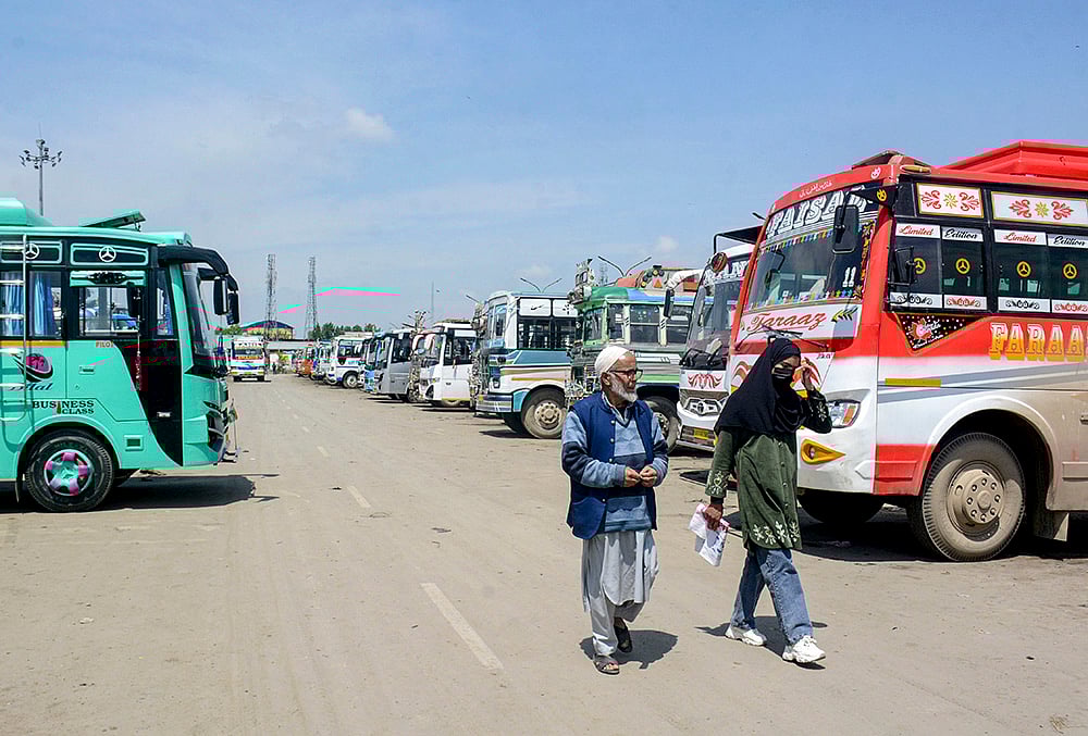 People walk past a bus stand after driver and conductors of private buses stage a protest against the government's proposal to expand Smart City bus services in other districts, in Srinagar, Jammu and Kashmir. - | Photo: PTI