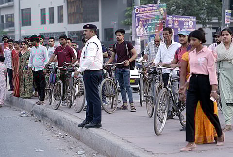 A policeman watches over labour returning back to their home after completing there shifts in factory at Noida Sec -63