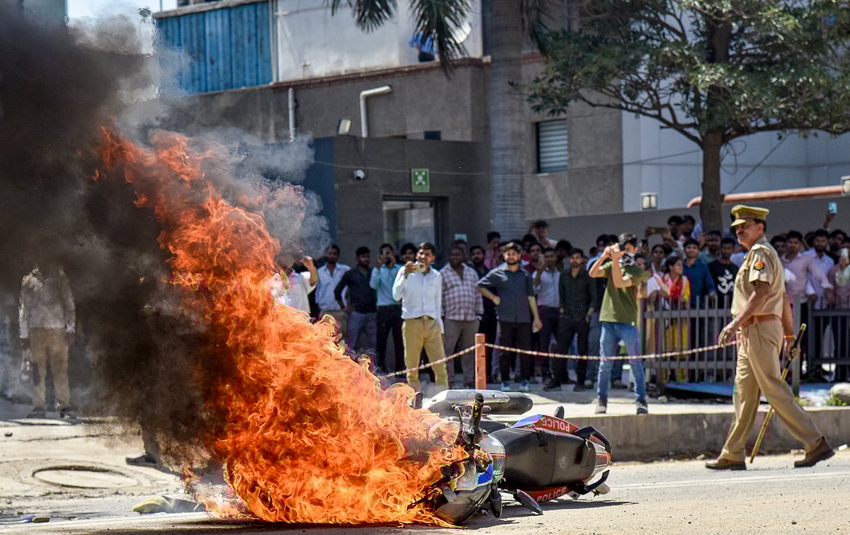 Flames billow as a police bike is set ablaze by factory workers during a protest demanding a hike in wages, in Noida, Gautam Buddh Nagar district, Uttar Pradesh, Monday, April 13, 2026. The protest carried incidents of arson, vandalism and stone-pelting reported from Phase-2 and Sector 60 areas, police said. - Source:  PTI