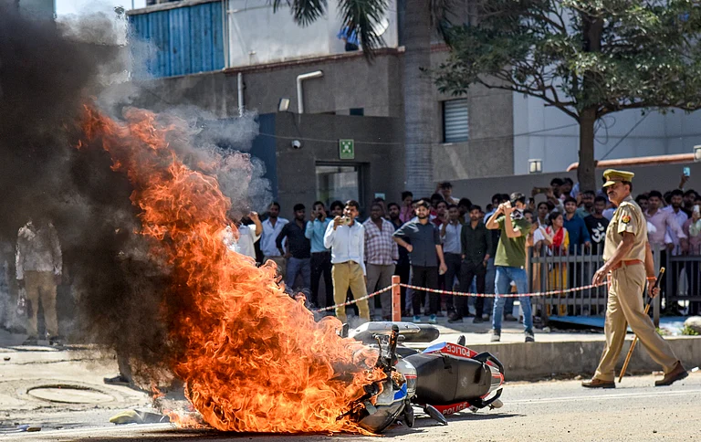 Flames billow as a police bike is set ablaze by factory workers during a protest demanding a hike in wages, in Noida, Gautam Buddh Nagar district, Uttar Pradesh, Monday, April 13, 2026. The protest carried incidents of arson, vandalism and stone-pelting reported from Phase-2 and Sector 60 areas, police said. - Source: PTI