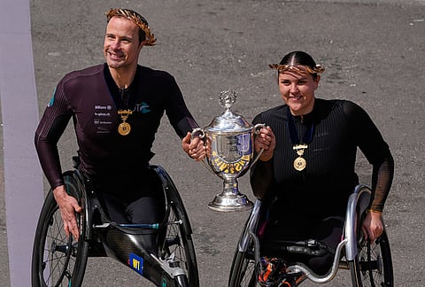Men's wheelchair division winner Marcel Hug, of Switzerland, left, and women's wheelchair division winner Eden Rainbow-Cooper, of Portsmouth, England, hold the trophy after competing in the Boston Marathon, in Boston.