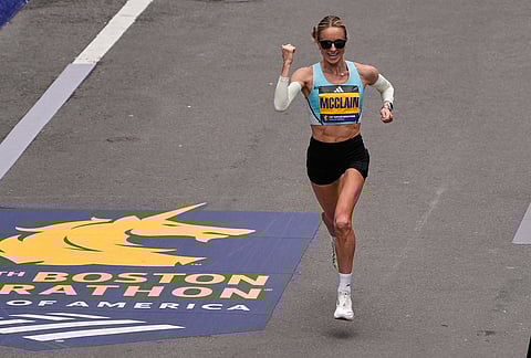 Jess McClain of Phoenix, the top American woman finisher, pumps her fist while approaching the finish line of the Boston Marathon, in Boston.