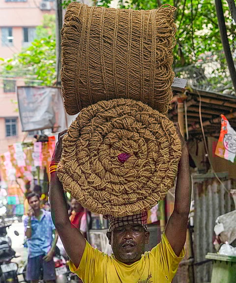 A man carries a load of jute mats on his head on a hot summer day, in Kolkata.