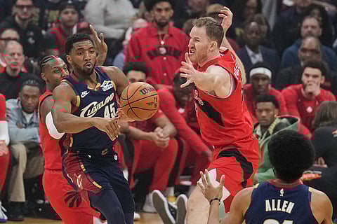 Cleveland Cavaliers guard Donovan Mitchell (45) passes the ball around Toronto Raptors center Jakob Poeltl, upper right, in the first half in Game 2 of a first-round NBA basketball playoffs series in Cleveland.
