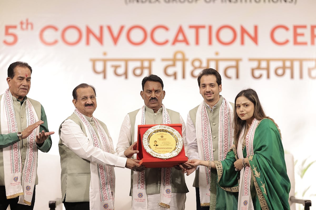 Five people on stage at a convocation ceremony holding a commemorative plaque.