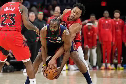 Cleveland Cavaliers guard James Harden, center, keeps the ball fron Toronto Raptors forward Scottie Barnes, right, in the second half in Game 2 of a first-round NBA basketball playoffs series in Cleveland.