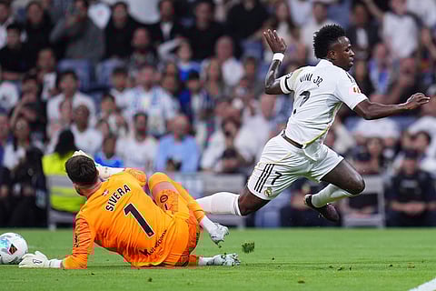Real Madrid's Vinicius Junior falls over Alaves' goalkeeper Antonio Siveraduring a La Liga soccer match between Real Madrid and Alaves in Madrid, Spain.