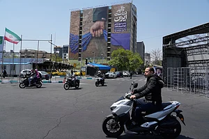 AP : Motorbikes drive past a billboard that shows a graphic depicting a military personnel's hand holding the Strait of Hormuz in his fist with signs which read in Farsi: "In Iran's hands forever," "Trump couldn't do a damn thing," "The control of Strait of Hormuz will be Iran's forever," in Vanak Square in northern Tehran, Iran, Thursday, April 16, 2026.