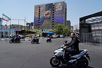 Islamabad Talks Stall But Ceasefire Holds AP : Motorbikes drive past a billboard that shows a graphic depicting a military personnel's hand holding the Strait of Hormuz in his fist with signs which read in Farsi: "In Iran's hands forever," "Trump couldn't do a damn thing," "The control of Strait of Hormuz will be Iran's forever," in Vanak Square in northern Tehran, Iran, Thursday, April 16, 2026.
