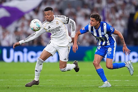 Real Madrid's Kylian Mbappe, left, and Alaves' Nahuel Tenaglia fight for the ball during a La Liga soccer match between Real Madrid and Alaves in Madrid, Spain.