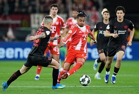 Leverkusen's Alex Grimaldo, left, and Bayern's Michael Olise challenge for the ball during the German Soccer Cup semifinal match between Bayer Leverkusen and Bayern Munich in Leverkusen, Germany.