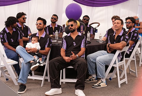 Unmurkt Chand holds his baby, Krishay, with members of the Los Angeles Knight Riders, cricket team form a LA sign with their hands as they pose for a picture at the Pomona Fairplex during the groundbreaking ceremony of the new Knight Riders Cricket Field, which will serve as the Los Angeles Knight Riders' official home field for 2026 and later host cricket at the LA 2028 Olympics.