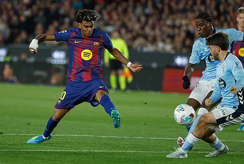 Barcelona's Lamine Yamal, left, shoots the ball during the Spanish La Liga soccer match between Barcelona and Celta Vigo in Barcelona, Spain.