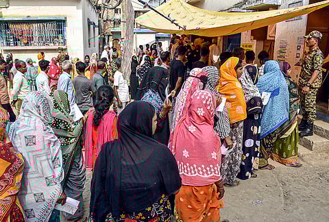 People wait in queues during voting in the first phase of the West Bengal Assembly elections, at a polling station in Murshidabad.