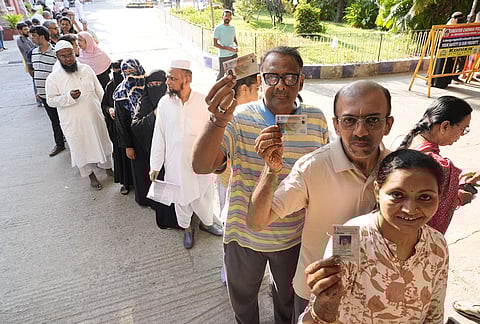Voters show their voter ID cards before casting their votes at a polling station during the Tamil Nadu Assembly elections, in Egmore.