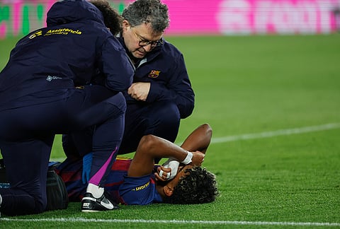 Barcelona's Lamine Yamal lies on the pitch injured during the Spanish La Liga soccer match between Barcelona and Celta Vigo in Barcelona, Spain.
