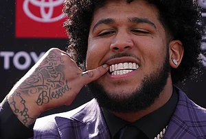 | Photo: AP/Gene J. Puskar : Alabama offensive lineman Kadyn Proctor shows off his dental jewelry while posing on the red carpet before the first round of the NFL football draft in Pittsburgh