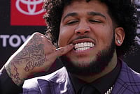 | Photo: AP/Gene J. Puskar : Alabama offensive lineman Kadyn Proctor shows off his dental jewelry while posing on the red carpet before the first round of the NFL football draft in Pittsburgh