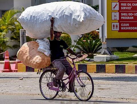 Chikkamagaluru: A commuter carrying bags of empty plastic bottles passes by on a cycle on a hot summer day, in Chikkamagaluru.