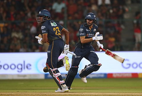 Gujarat Titans' captain Shubman Gill with batting partner Sai Sudharsan run between the wickets to score during the Indian Premier League cricket match between Royal Challengers Bengaluru and Gujarat Titans in Bengaluru.