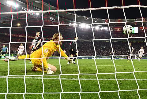 Freiburg goalkeeper Florian Mueller looks back as the ball goes into the net for the winning goal by Stuttgart's Tiago Tomas during a German Cup semifinal soccer match between VfB Stuttgart and SC Freiburg, in Stuttgart, Germany. 