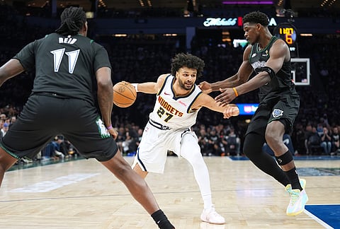 Denver Nuggets guard Jamal Murray (27) works toward the basket as Minnesota Timberwolves center Naz Reid (11) and guard Anthony Edwards (5) defend during the first half in Game 3 of a first-round NBA basketball playoff series, in Minneapolis.