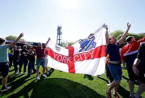 York City fans celebrate on the pitch at the final whistle after the National League match between Rochdale and York City in Rochdale, England.