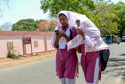 Students cover themselves amid heat during the summer season, in Bhopal, Madhya Pradesh.