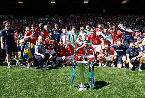 York City players and staff celebrate with the trophy after defeating Rochdale in the National League match in Rochdale, England.