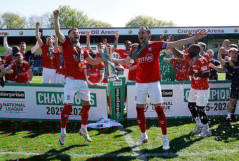 York City players and staff celebrate with the trophy after defeating Rochdale in the National League match in Rochdale, England.