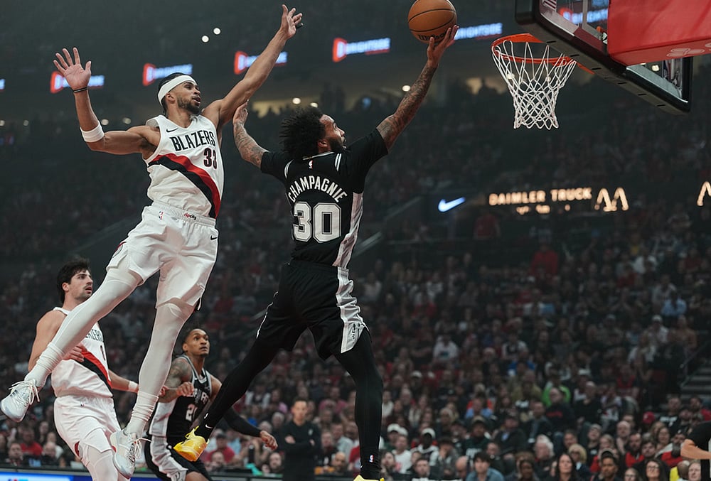 San Antonio Spurs forward Julian Champagnie (30) drives to the basket past Portland Trail Blazers forward Toumani Camara (33) during the second half in Game 3 of a first-round NBA playoffs basketball series in Portland, Oregon. - | Photo: AP/Jenny Kane
