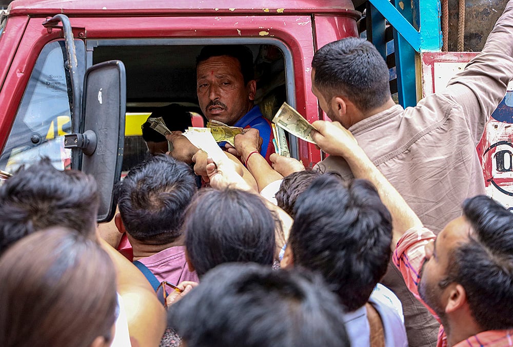 People rush to pay and collect LPG cylinders from a delivery truck carrying cylinders amid the ongoing supply crisis, at the McLeodganj Chowk, in Dharamshala, Himachal Pradesh. - | Photo: PTI