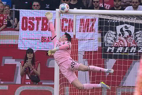 Bayern's goalkeeper Jonas Urbig dives as ball hits the post during a Bundeliga soccer match between Mainz and Bayern in Mainz, Germany.