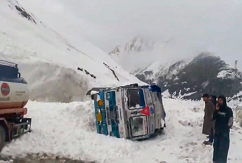 Security officials gather near an overturned vehicle after an avalanche hit the Srinagar-Leh national highway at Shaitan Nallah, in Jammu and Kashmir.