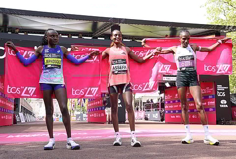 Winner Tigst Assefa of Ethiopia, center, second placed Hellen Obiri of Kenya, right and third placed Joyceline Jepkosgei of Kenya celebrate after the women's race at the London Marathon in London.