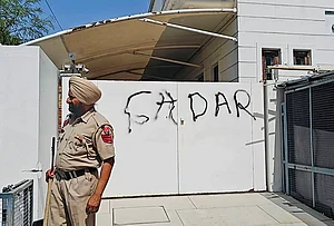 | Photo: PTI : A police official stands guard after AAP workers allegedly wrote 'Gaddar', a traitor, with spray paint on the entrance gate of Rajya Sabha MP Harbhajan Singh, a day after he quit the former party and joined the BJP, in Jalandhar, Punjab.