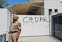 | Photo: PTI : A police official stands guard after AAP workers allegedly wrote 'Gaddar', a traitor, with spray paint on the entrance gate of Rajya Sabha MP Harbhajan Singh, a day after he quit the former party and joined the BJP, in Jalandhar, Punjab.