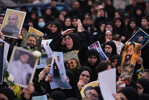 A woman mourns as other hold portraits of Hezbollah fighters, who were killed before the ceasefire in the war between Hezbollah and Israel, during a mass funeral procession in the southern village of Kfar Sir, Lebanon, Tuesday, April 21, 2026. 