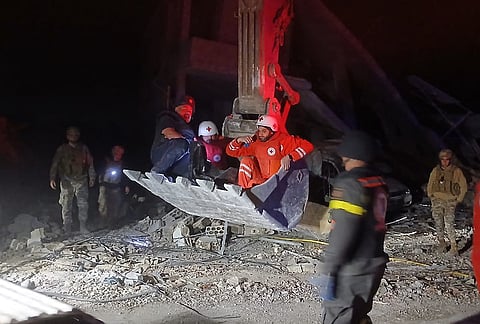 This photo released by the Lebanese Civil Defense, show Lebanese Red Cross volunteers and a Civil Defense worker sit on a excavator carrying the body of the Lebanese journalist Amal Khalil working for the daily Al-Akhbar newspaper killed in an Israeli airstrike, in al-Tiri village, south Lebanon, Wednesday, April 22, 2026. 