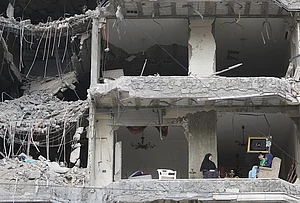 | Photo: AP/Hassan Ammar : The wife and children of Fadi Al Zein, who lost both his homes in Israeli strikes in his village of Khiam and in Dahiyeh, sit on the balcony of their heavily damaged apartment building in Beirut's southern suburbs, Lebanon, Saturday, April 25, 2026.
