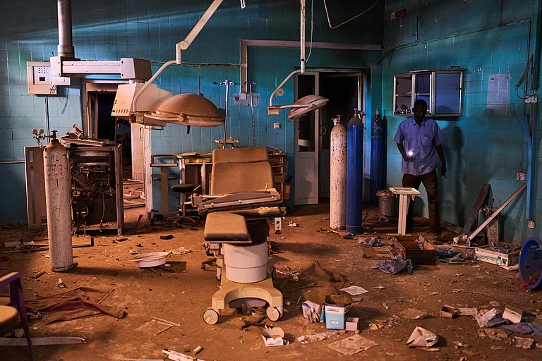 A guard walks through a war-damaged section of Al Shaabi Hospital in Khartoum - AP