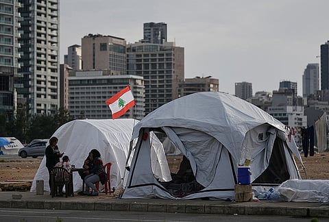 Displaced people who fled Israeli strikes in southern Lebanon sit outside shelter tents in Beirut, Lebanon, Friday, April 24, 2026. 