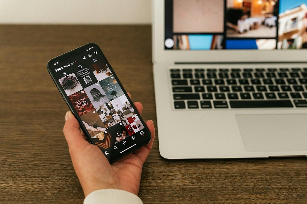 Hand holding a phone displaying an Instagram profile grid