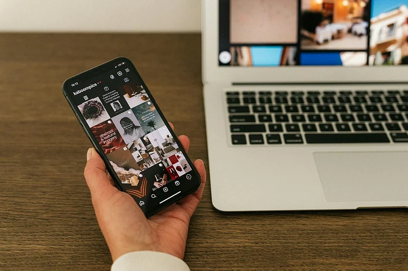 Hand holding a phone displaying an Instagram profile grid