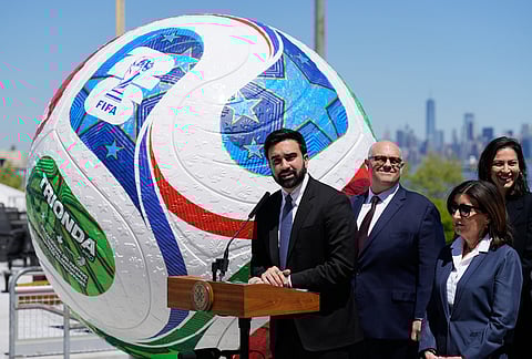 New York City Mayor Zohran Mamdani, left, speaks in front of a large soccer ball the city skyline during a news conference in the Staten Island borough of New York.