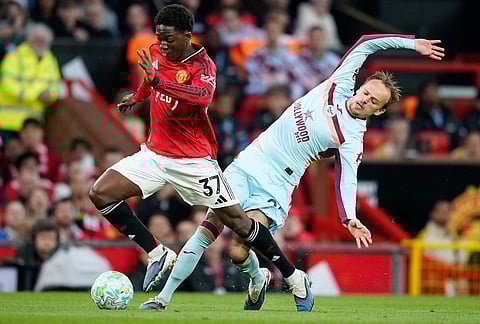 Manchester United's Kobbie Mainoo, left, and Brentford's Mikkel Damsgaard fight for the ball during the Premier League soccer match between Manchester United and Brentford in Manchester, England.